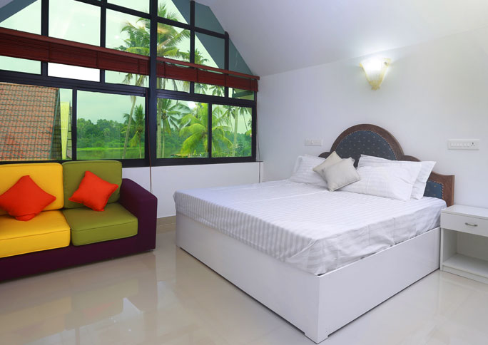 Bedroom with double bed and sofa by a tall glass window